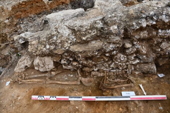 Vue d'une sépulture recoupée par un mur de cave. Mantes-la-Jolie, Place du Marché au Blé