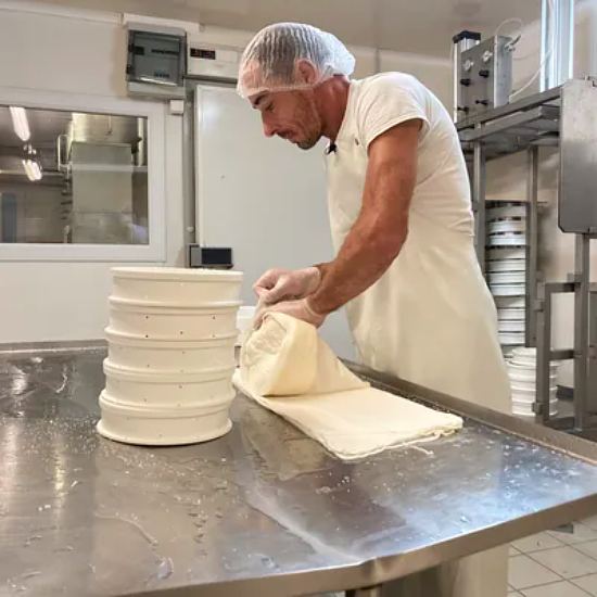 Christophe, fromager, enveloppe les saint-nectaire dans une toile de lin lors de la phase de moulage